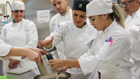 Student with chefs learning culinary techniques
