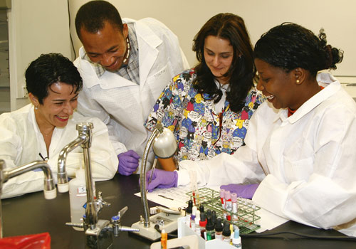 Rosa Castro, an assistant professor of clinical laboratory technology (multi-colored scrubs) works with biologists from Mozambique.