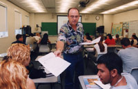 Professor Chris Migliaccio hands out papers in his class.