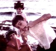 Home movie still showing children on a beach.