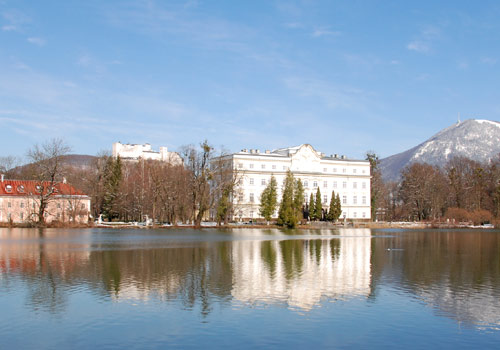 The historic Leopoldskron Palace, nestled by a small lake and offering majestic mountain views.