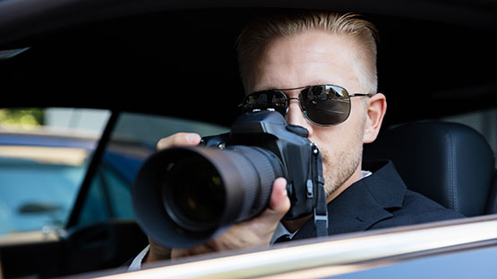Private investigator sitting in a car holding a camera