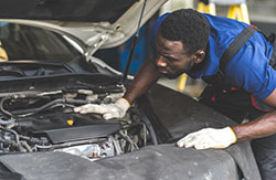 Automotive Service technician works on the front of a car