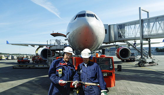 Two air mechanics, engineers, with large airliner in background, airport ground activities