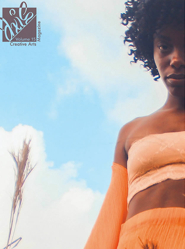 A young African American woman poses in a field with a beautiful blue background