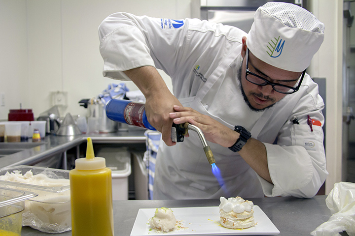 Miami Culinary Institute student aplying the Flambe technique on a dessert