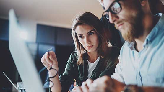 Man and woman sitting at a desk in front of a computer