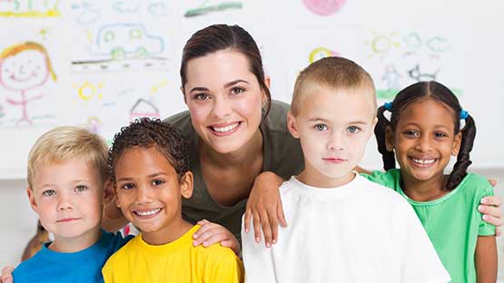 Teacher smiling with group of pre-school 
students