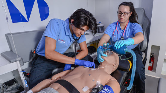 Two emergency Meedical Services personnel,transporting a woman on a stretcher.