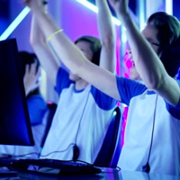 Two young men raise their hands in celebration as they play online esports
