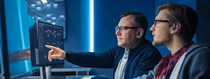 Teachers in front of computer pointing at cybersecurity data