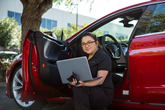 Woman using laptop outside of her car