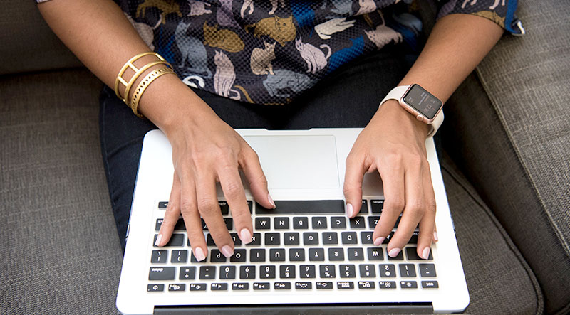 Woman shown using a computer while wearing a smartwatch.