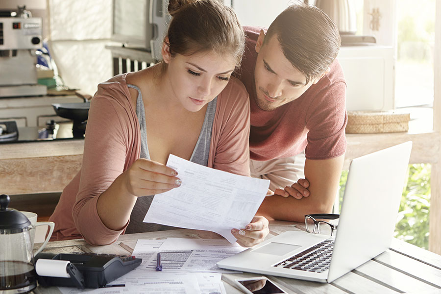 Photo of a young couple in their home kitchen, working on their household budget together