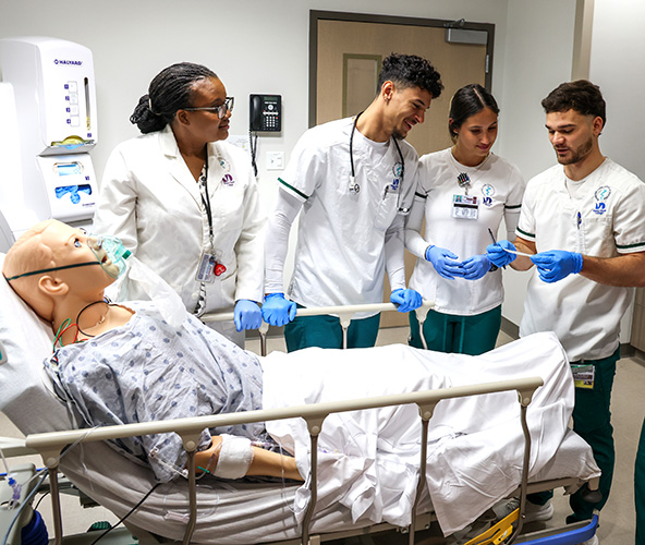 Students and instructor collaborating around a medical simulator