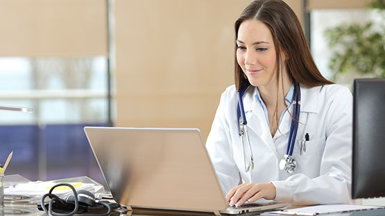 Medical professional sitting at desk working on a computer