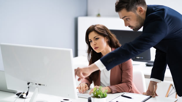 Two co-worders review a client's resume on a computer