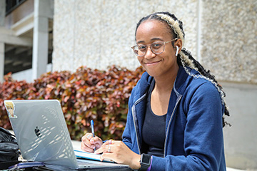 Student with a laptop smiling 