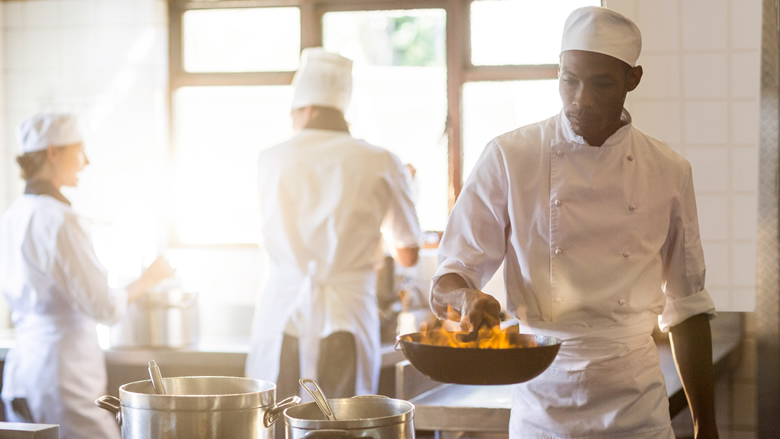 Chef handles a pan over a high flame