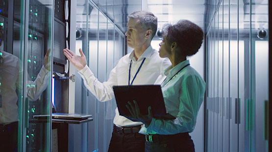 Man and woman working on a server inside a data center