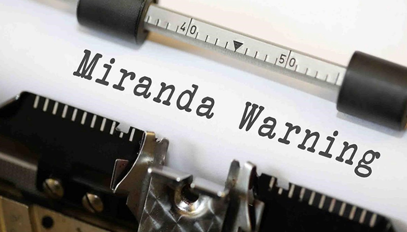 Close up of a manual typewriter that has the word Mirand Warning typed out