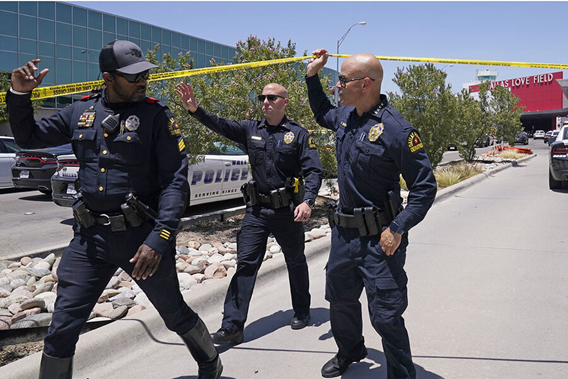 Officer answers phone in control operations area surrounded my electronic equipment and other staff