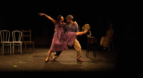 Two actors dancing on stage during theatrical performance