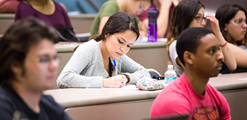 Student in classroom taking notes