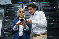 Two students in a server room looking at a phone