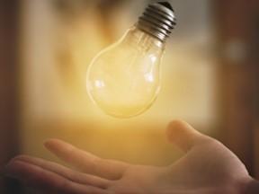 illuminated lightbulb floating over an open hand