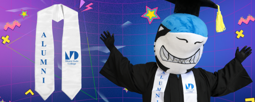 MDC Shark mascot, Finn, in a cap and gown, promoting an Alumni stole.