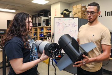 Two students holding plastic components from a project