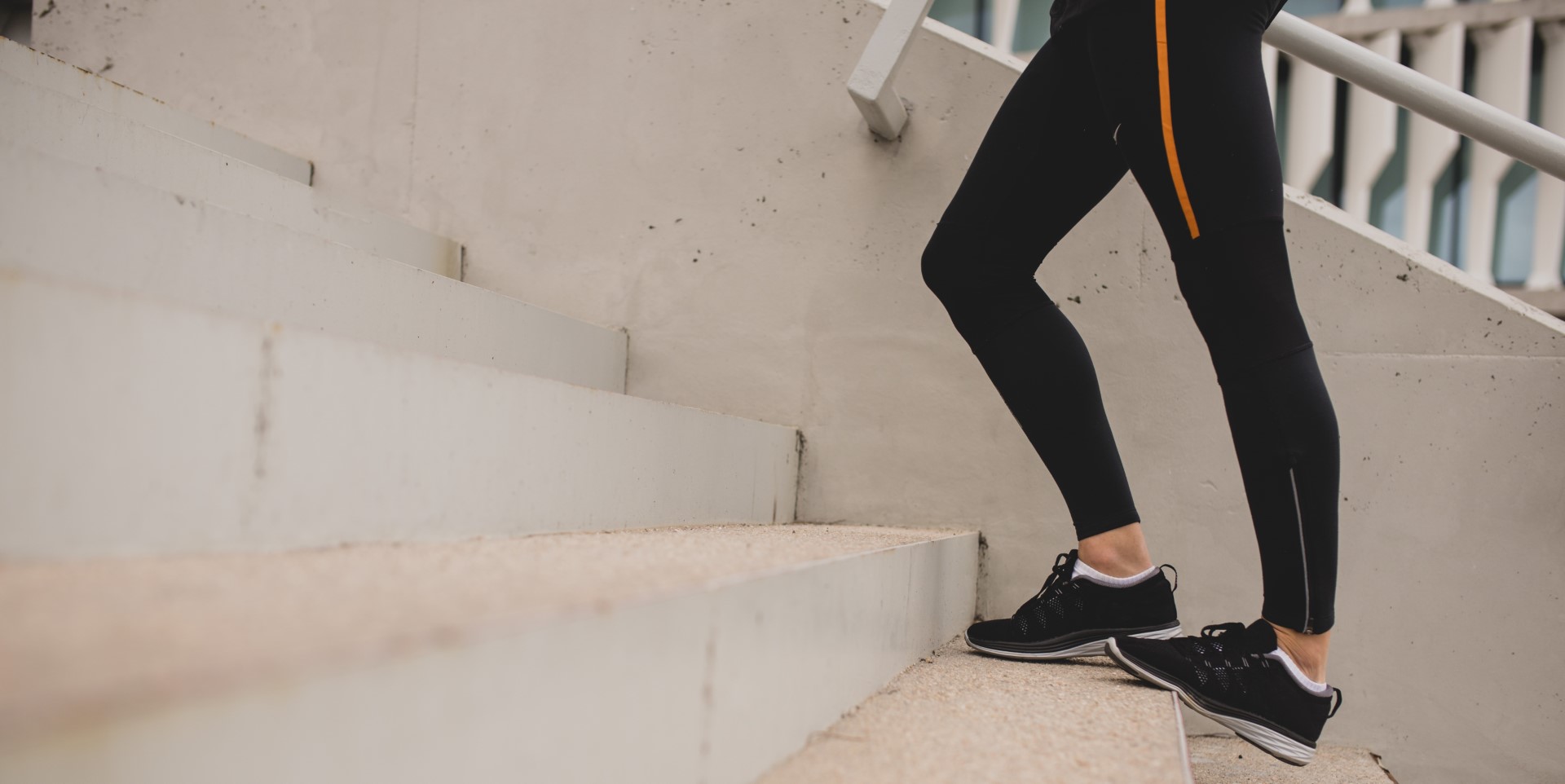 A woman on the stairs stretches her calf muscles