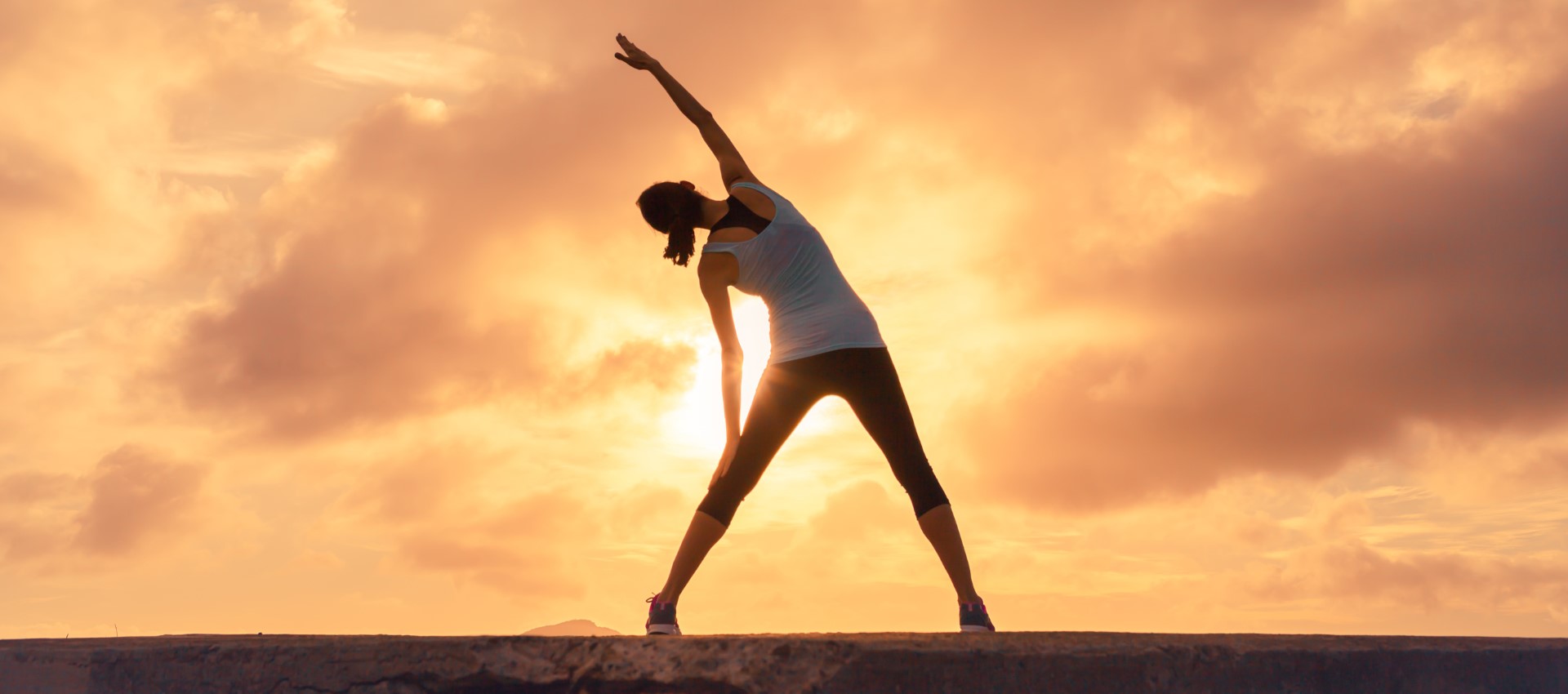 Silhouette of a woman stretching at sunrise
