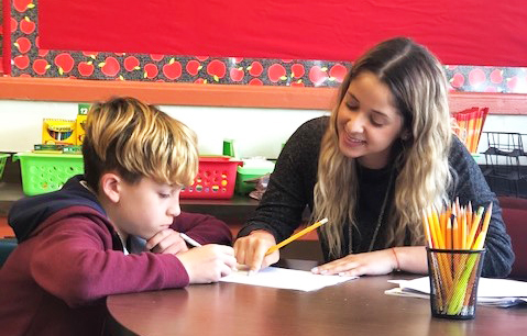 Teacher helping young student with classwork