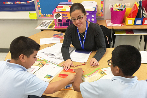 Teacher assisting two students with classwork
