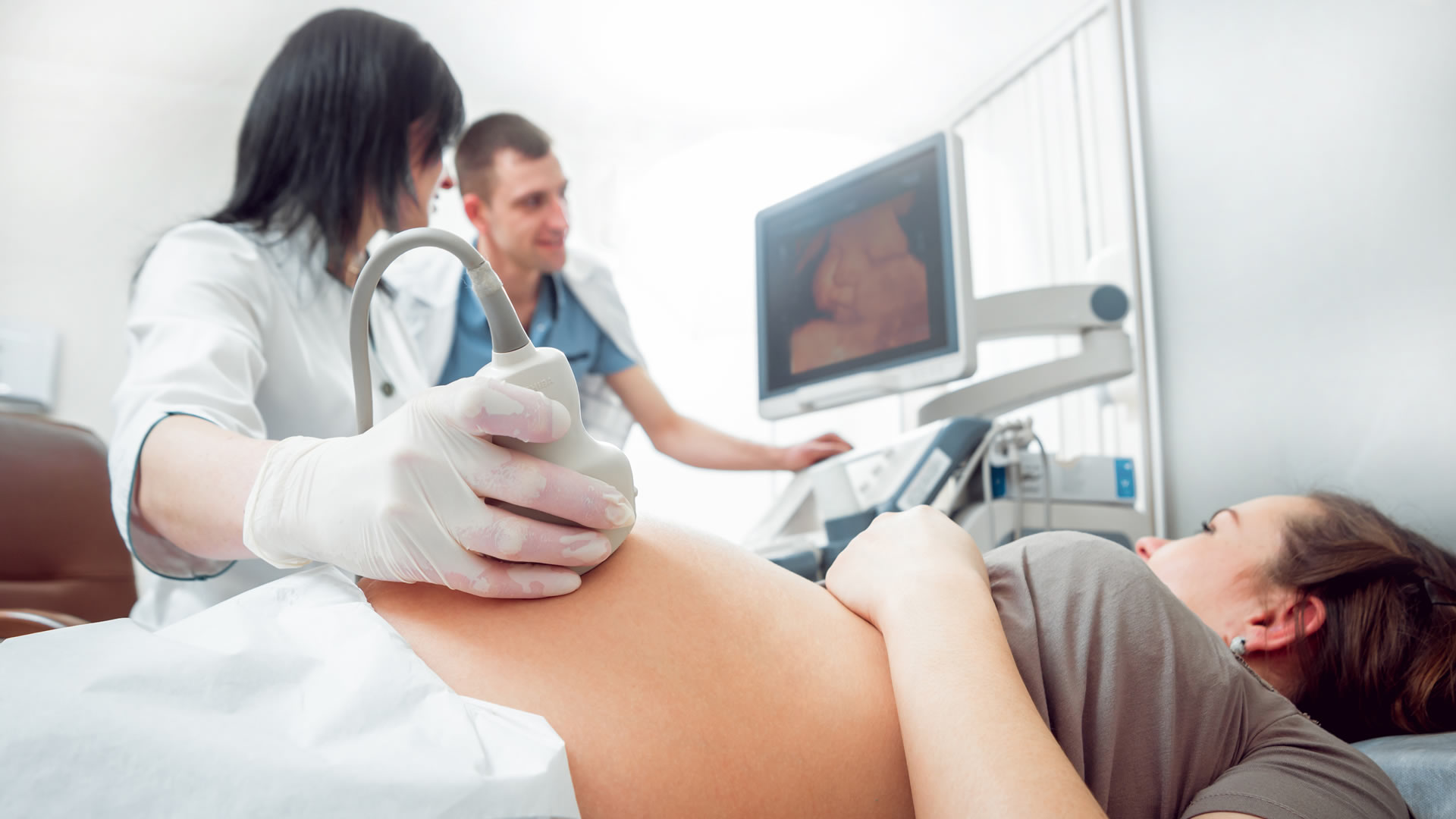 A student practices giving an ultrasound to a pregnant patient