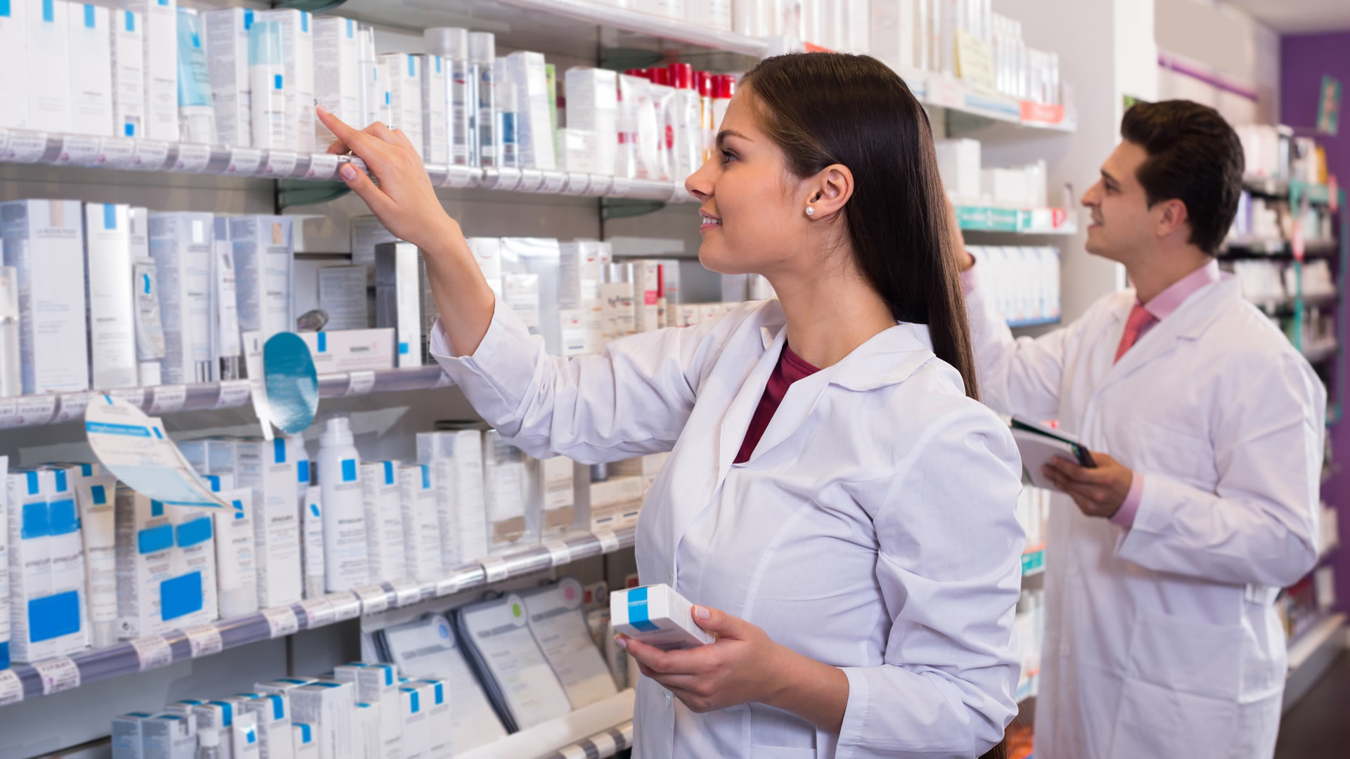 A female pharmacist assistant locates medication for a patient