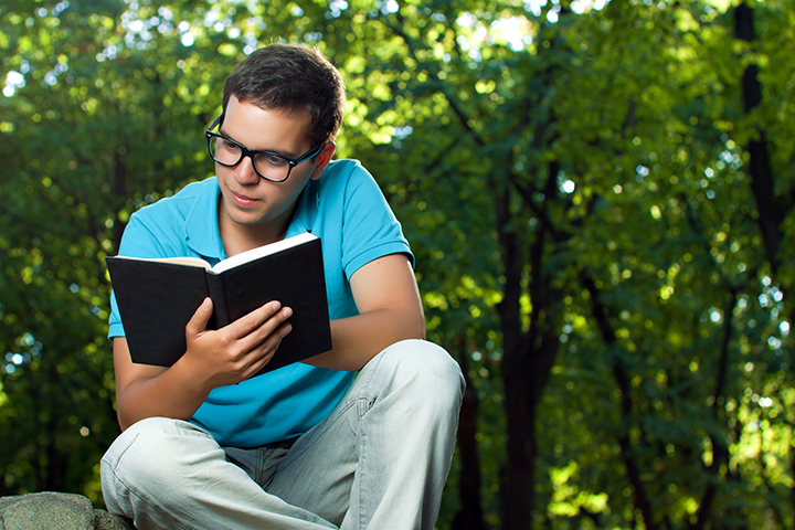Student sitting on a garden reading a book