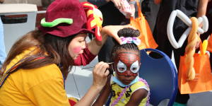 Clown painting the face of a child at the Community Health Fair