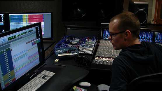 Student in a music studio working with a production console