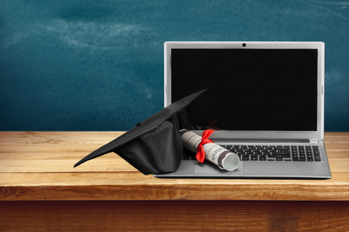 graduation cap and diploma resting on laptop
