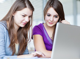 two girls sharing a laptop