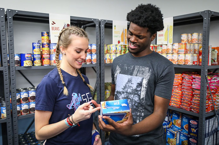 Two student volunteers review food at the pantry