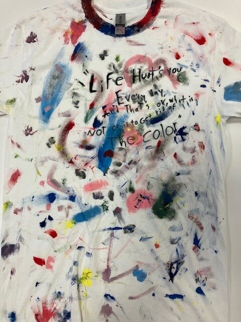 white tee shirt with the words 'life hurts you every day, and that's okay. what is not okay is to get rid of the color' hand painted on it