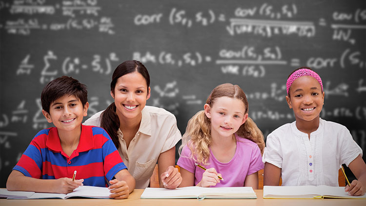 Teacher with 4 kids on her desk smiling.