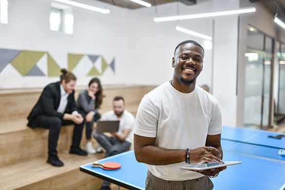 Woman standing besides a pingpong table, with three man in the background