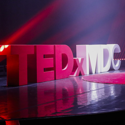 Large TedxMDC logo on a stage