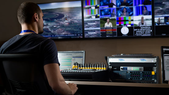 Man sitting in a television production studio in front of console