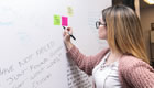 Female student writing on whiteboard
